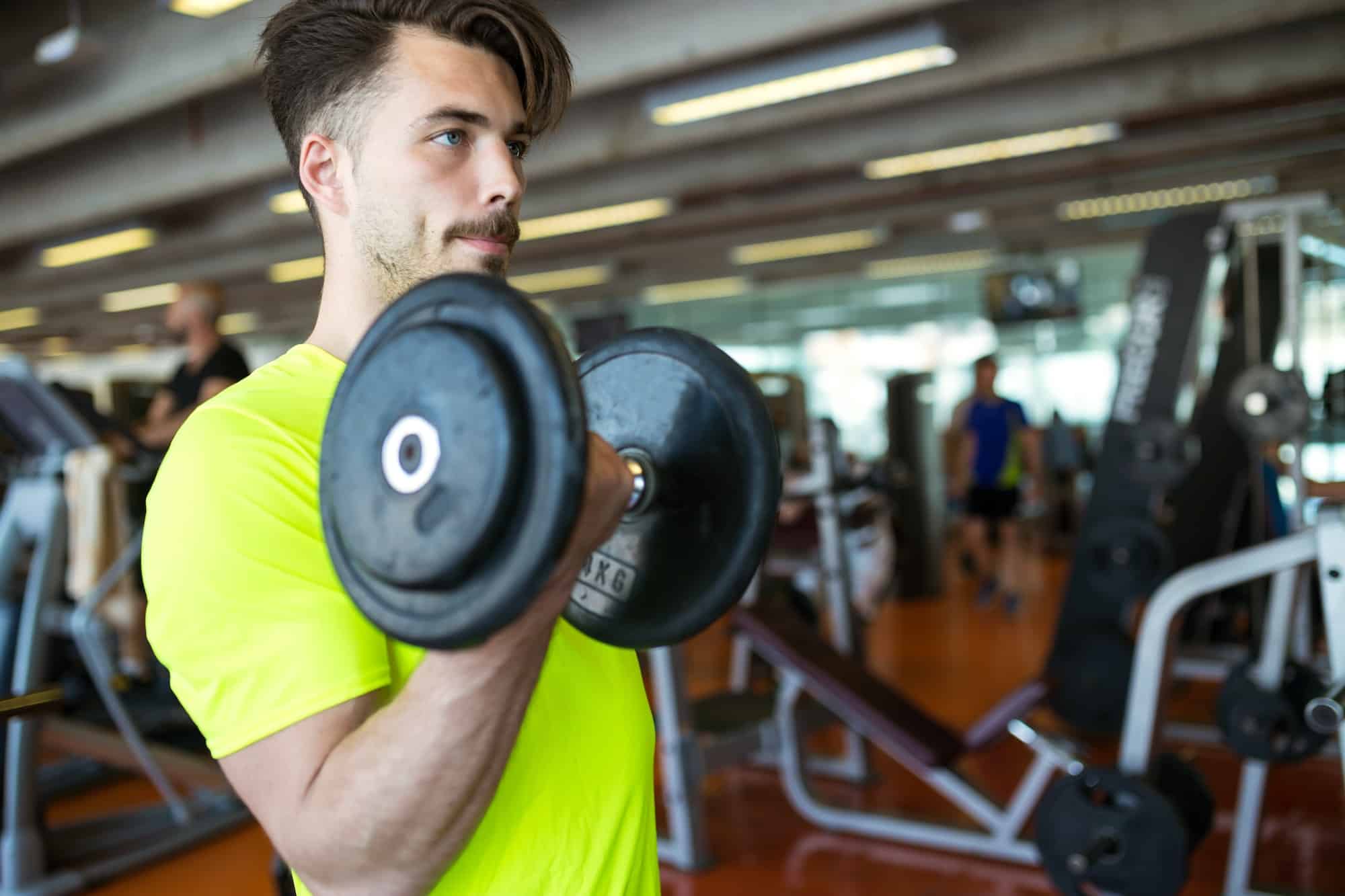 Handsome young man doing muscular exercise in gym.